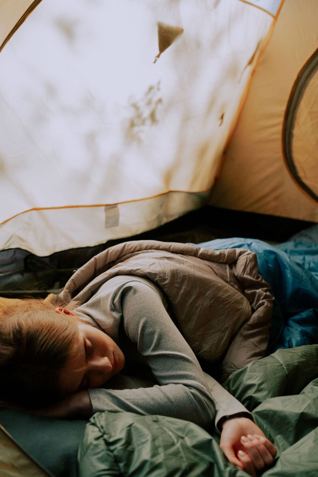 Camper sleeping soundly in a tent under layered sleeping bags