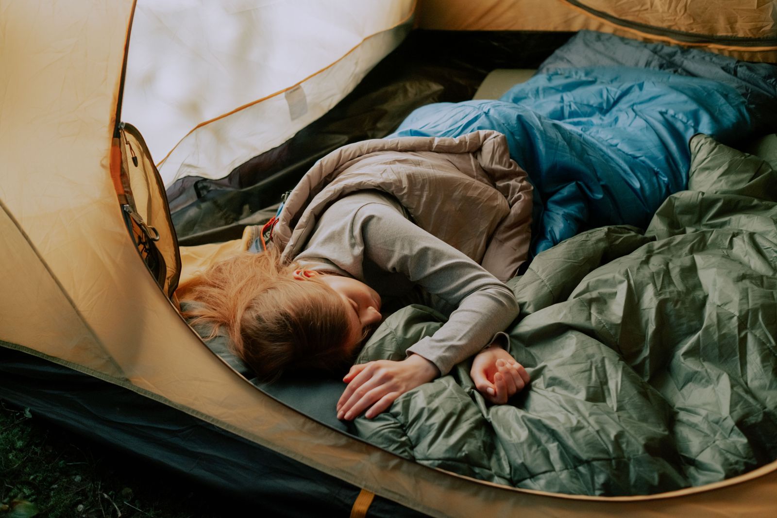 Layered blue, taupe and green sleeping bags inside a camping tent