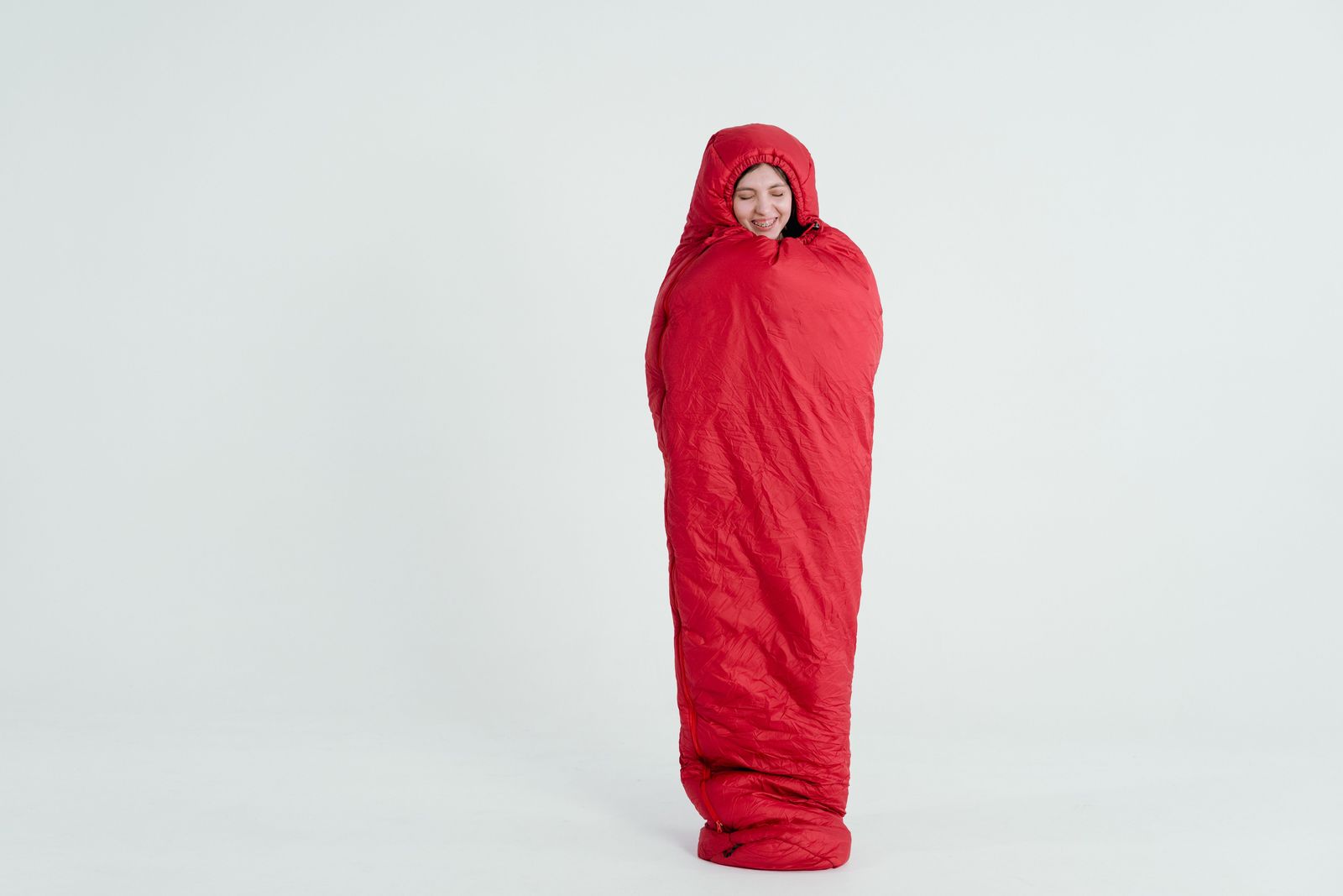 Person wearing a red hooded mummy sleeping bag